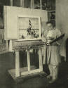 caption: N. C. Wyeth posed in his studio, with "Columbus Discovers America" on the easel (photo…